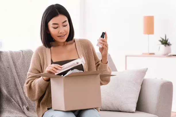 woman pulling makeup out of cardboard box
