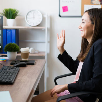 woman smiling and waving while she is on a video call