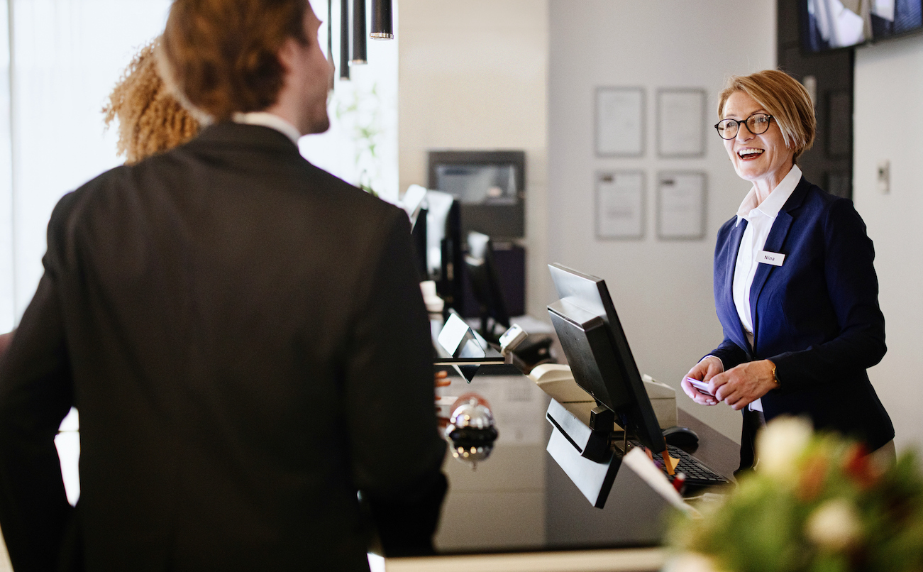 travelers checking into a hotel after having a positive experience with an outsourced travel & hospitality contact center