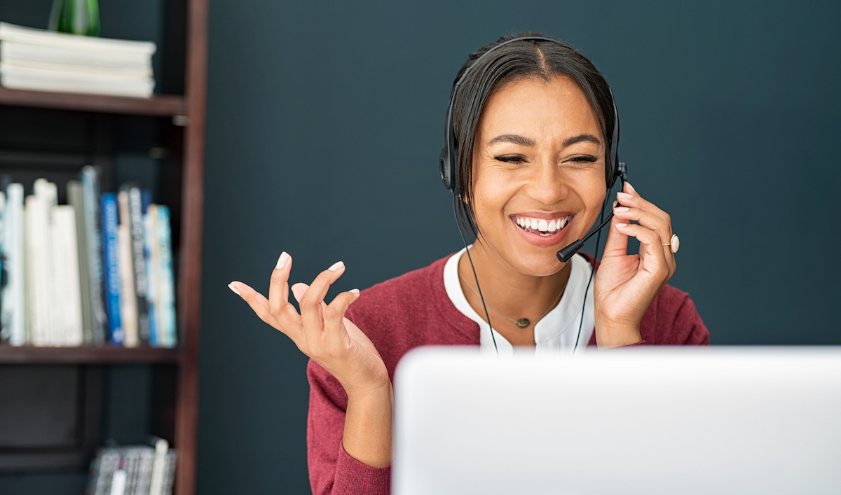 a business owner using their laptop to work on their customer service goals while talking on a headset