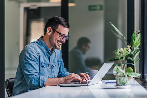 a business owner working at his laptop, happy with their decision to utilize nearshoring services