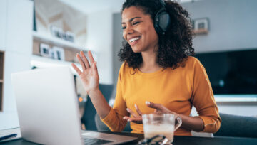 a person at their computer, wearing a headset researching information about customer orientation