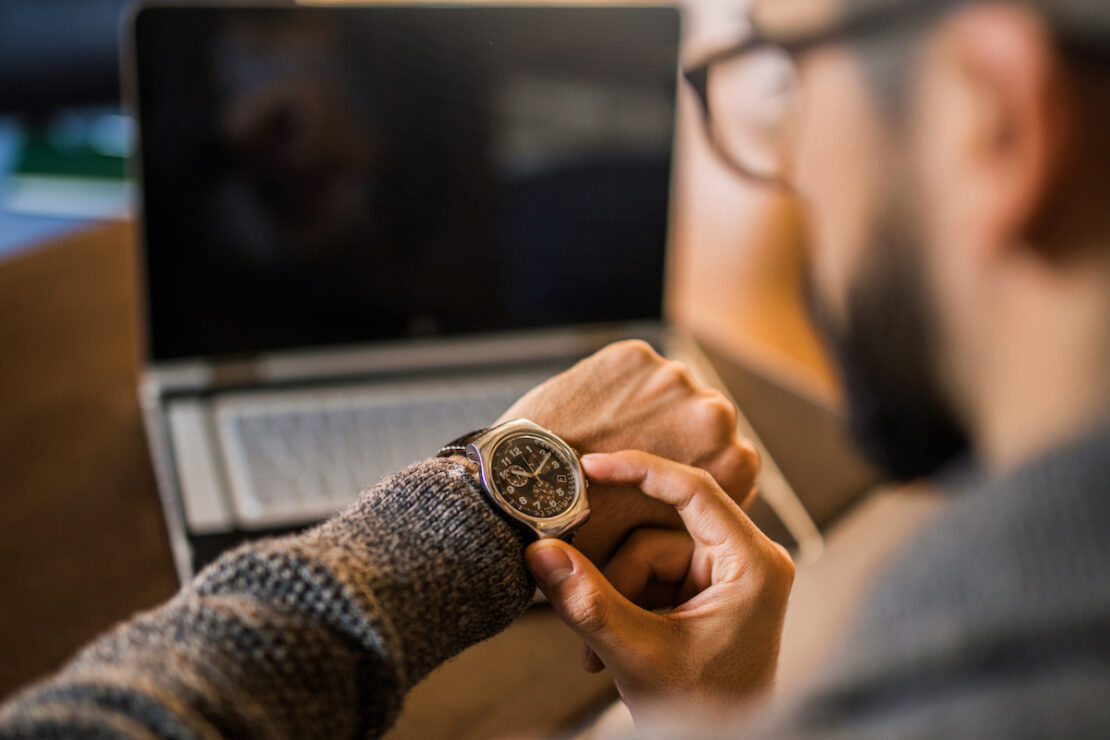 a person checking their watch, tracking their call center's average handle time.