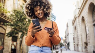 a person benefiting from a luxury retail brand's clienteling strategy while they make a purchase using their credit card outdoors