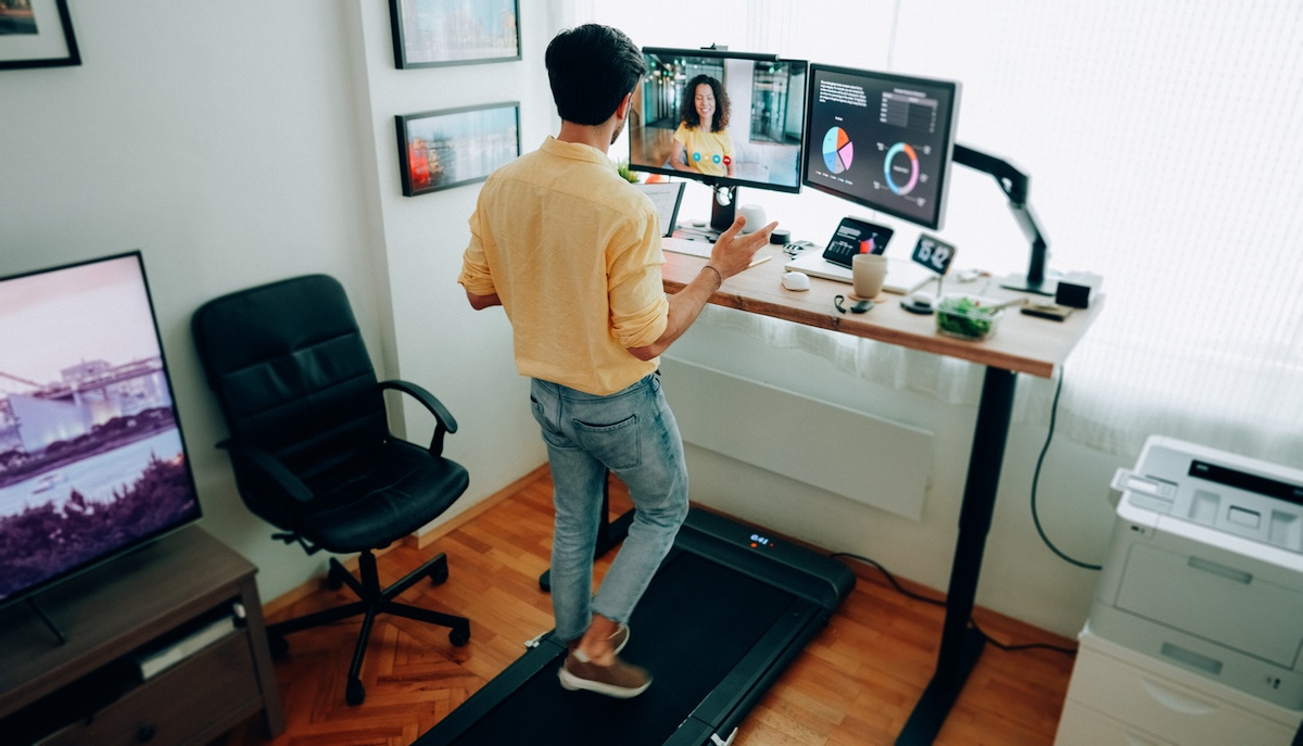 a person working at a walking desk while discussing call center BPO services with colleagues via a video meeting