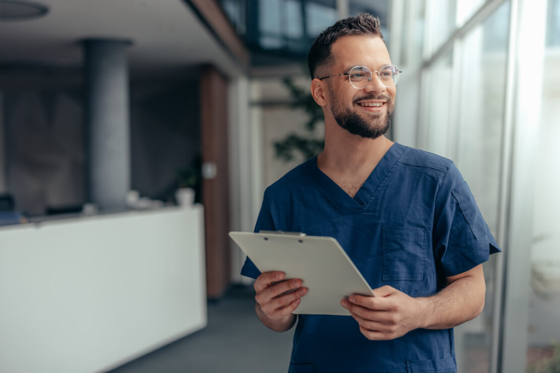 A doctor looks up from a clipboard and smiles confidently.