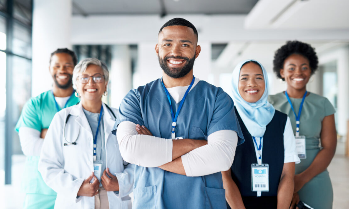 A group of healthcare professionals from various specialties and disciplines smile at the camera.