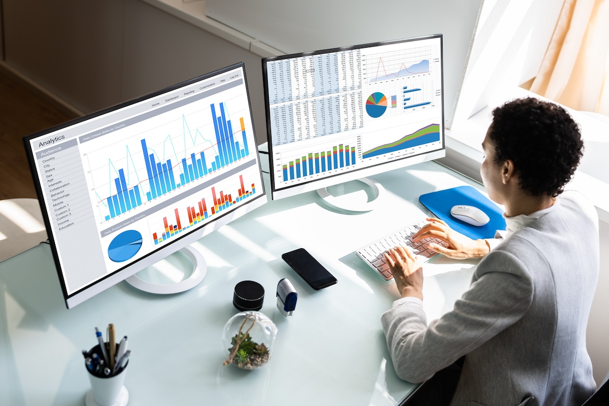 a call center agent reviewing a call center optimization report across 2 monitors