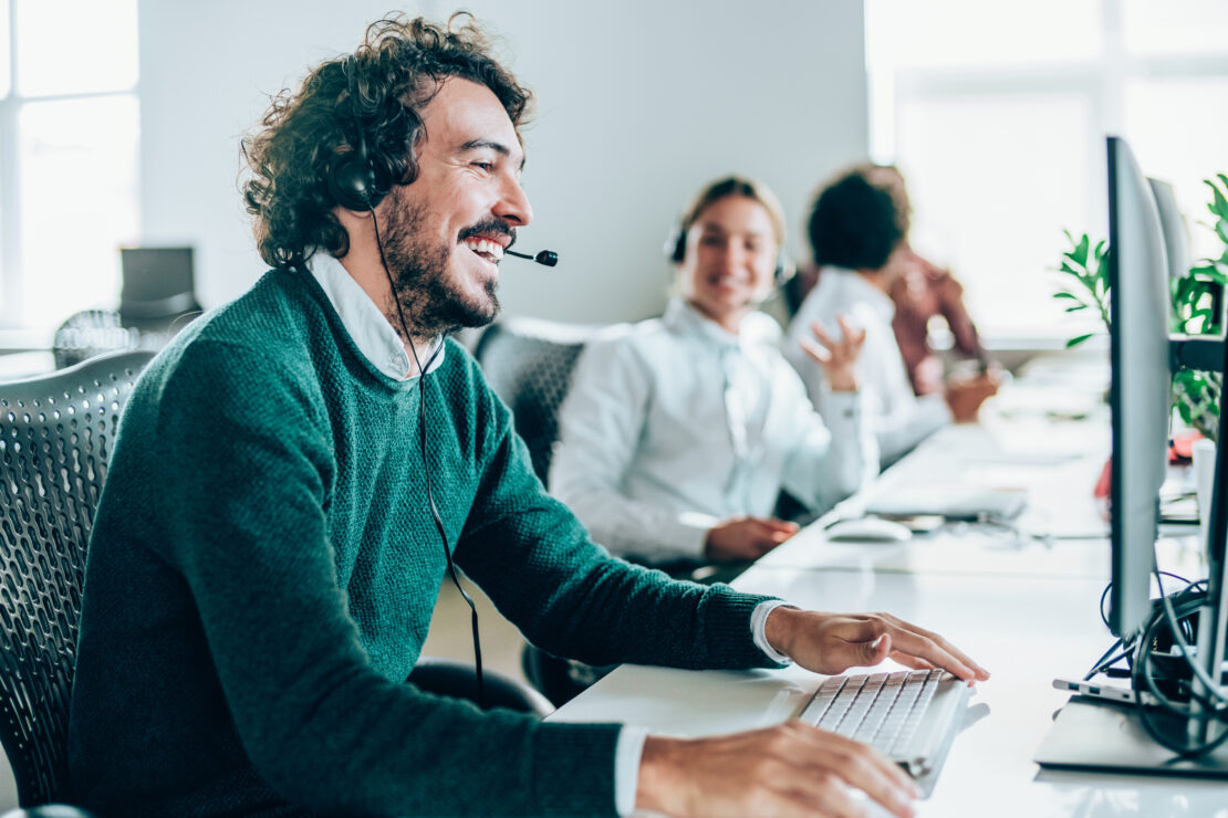 A customer service rep laughs during a pleasant interaction with a customer.