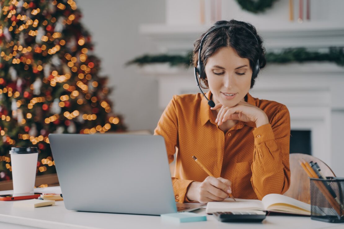 Customer service agent on laptop in front of Christmas tree