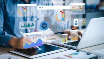Analyst viewing a data dashboard with computer and smart pad.