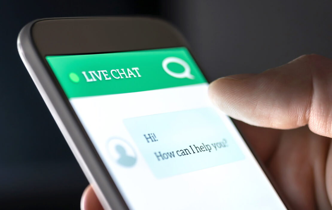 Hand holding phone engaged in live chat customer service