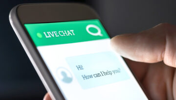 Hand holding phone engaged in live chat customer service
