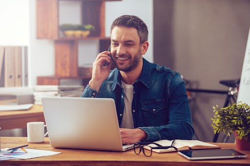 Satisfied male customer speaking on the phone and working on a computer