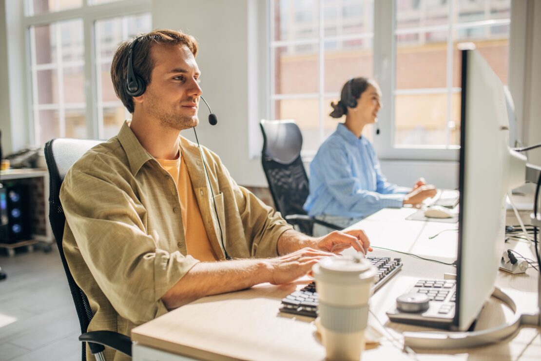 Two agents answering calls and messages in a sunlit open-concept office.