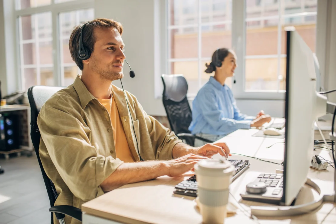 Two agents answering calls and messages in a sunlit open-concept office.