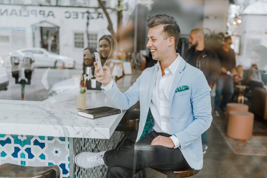 Smiling man looking at smartphone in a cafe