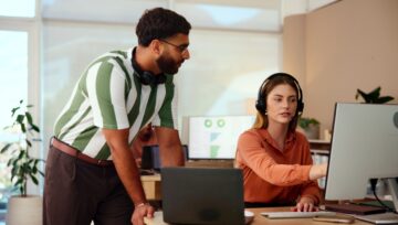 2 customer service agents talking and pointing at a computer screen