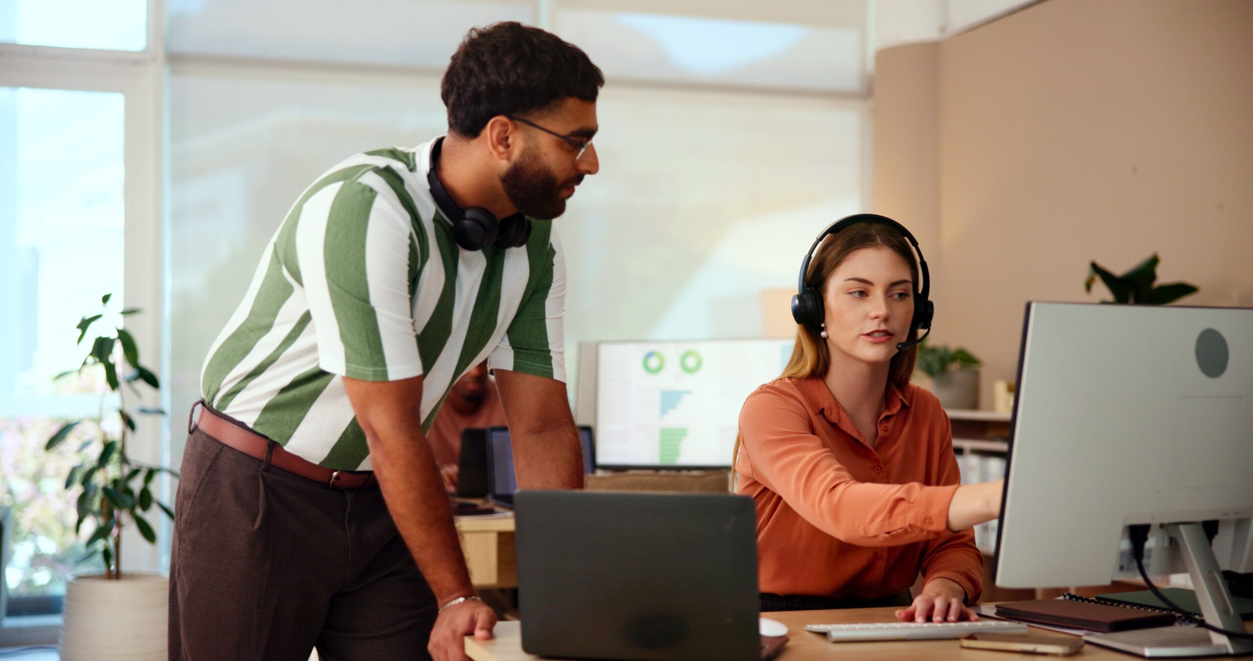 2 customer service agents talking and pointing at a computer screen