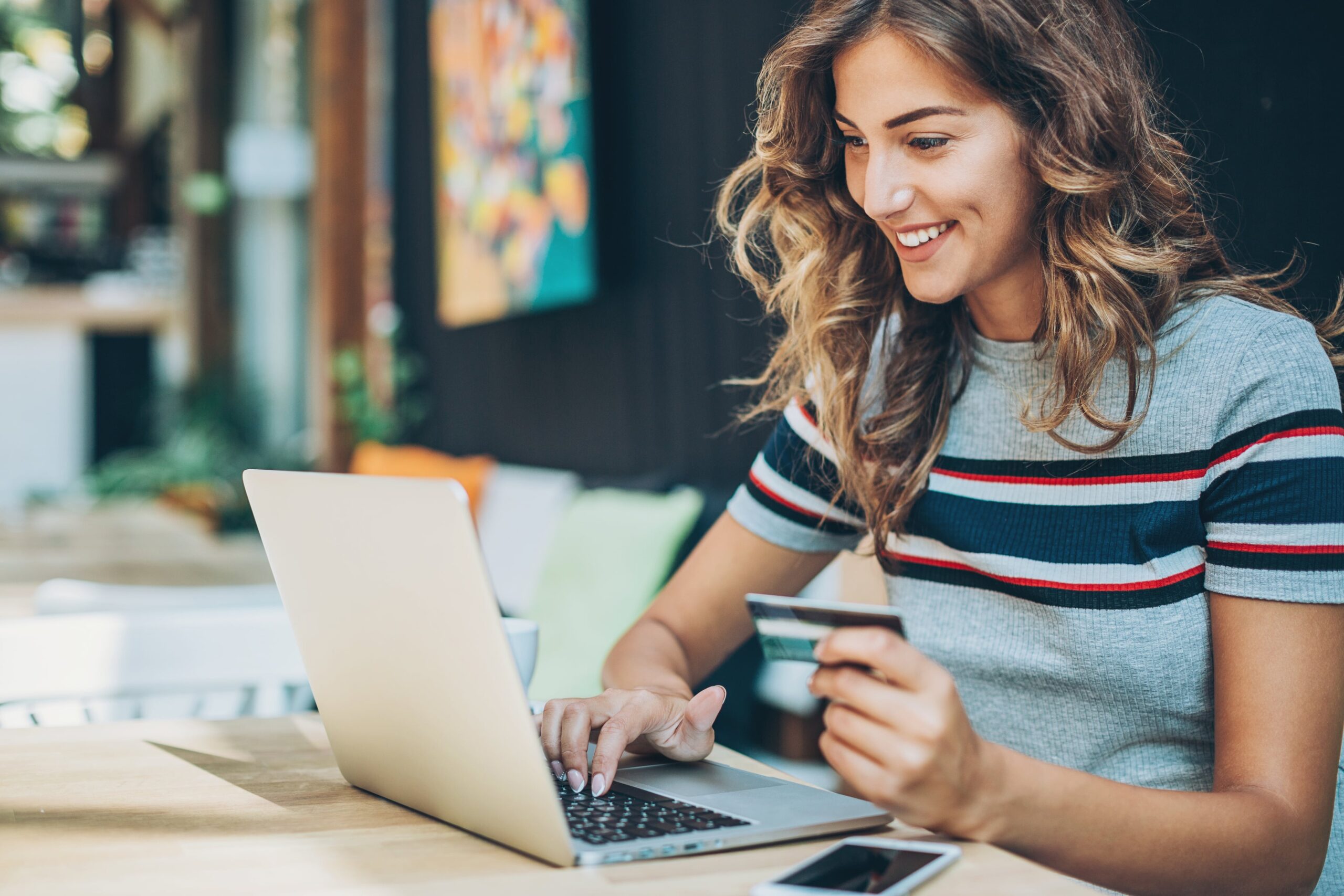 young woman customer smiling while buying something on her computer
