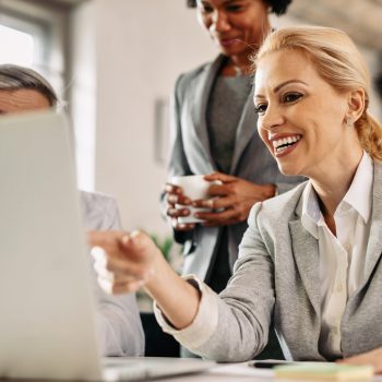 Happy businesswoman and her colleagues working on the computer during a meeting in the office.