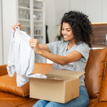 woman holding up shirt from box