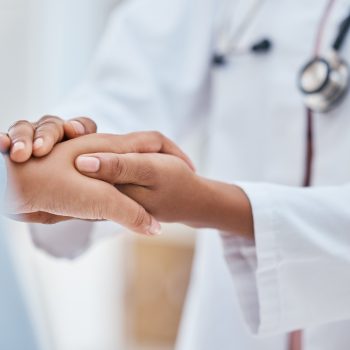 a doctor that utilizes a HIPAA compliant call center holding the hand of a patient.