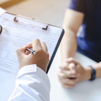 a doctor that uses a HIPAA compliant call center writing notes on a clipboard