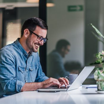 a business owner working at his laptop, happy with their decision to utilize nearshoring services