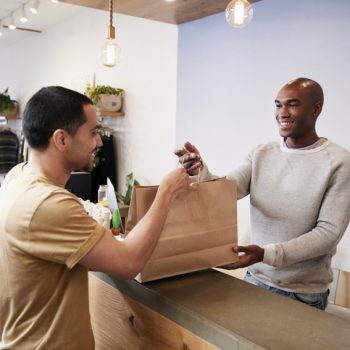 man handing another man a shopping bag